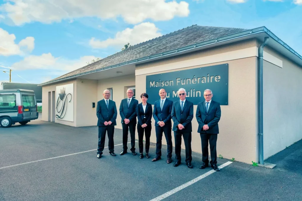 Équipe professionnelle de conseillers et porteurs funéraires devant l'agence.